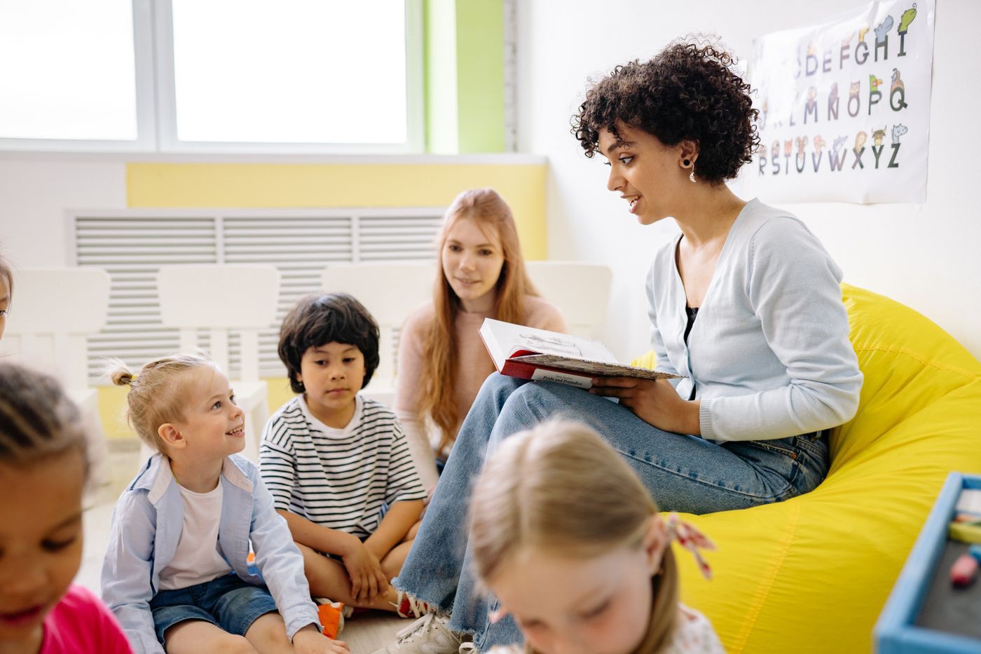 Practitioner reading with a group of young pupils in an early years setting